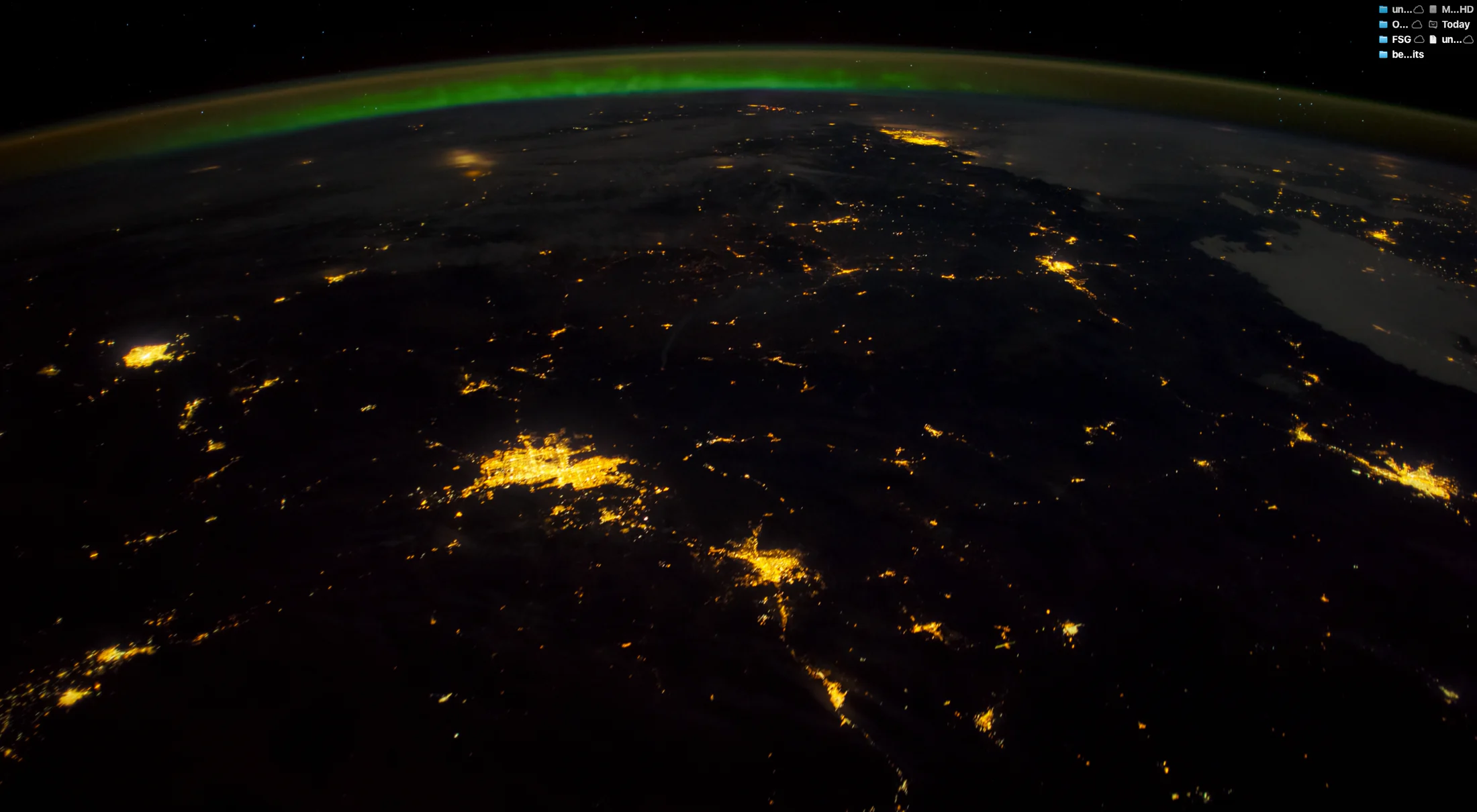 Earth at night beneath a green aurora
